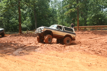 1992 Ford Mustang - A modified SUV navigates a muddy terrain with large tires, showing off its off-road capabilities.