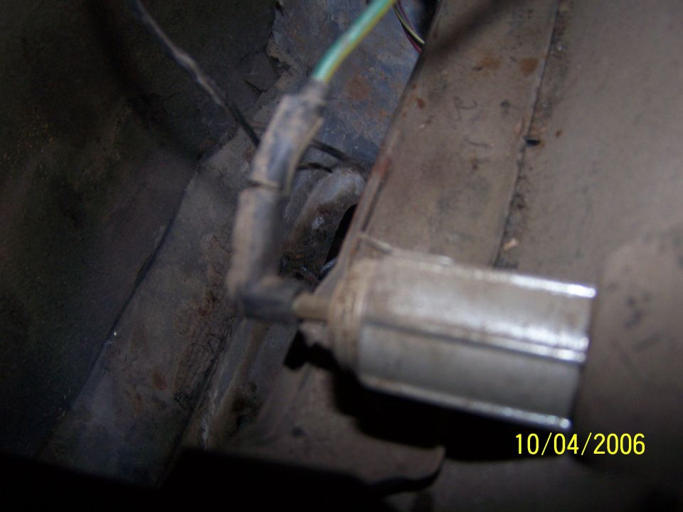 Close-up of an automotive electrical component with wires attached, showing rust and dirt