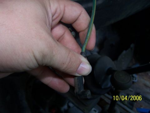 1979 Ford F-150 - A hand is shown holding a spark plug wire, with other engine parts visible in the background.