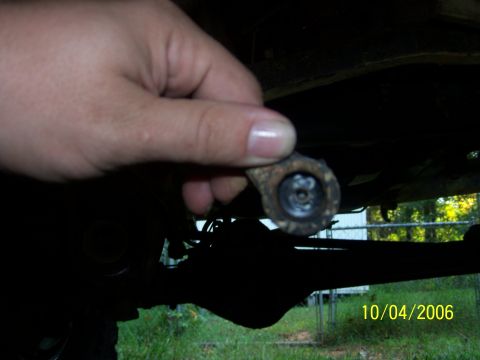 1979 Ford F-150 - A hand holds a small metal component, possibly a suspension part, near the rear axle of a vehicle.