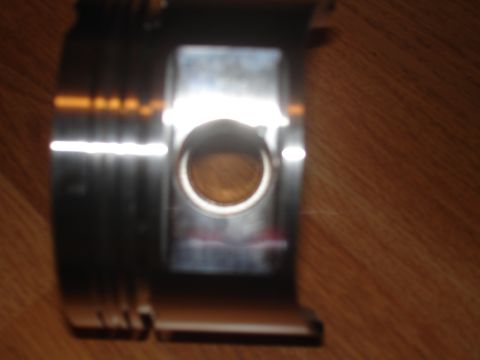 1994 Ford Probe - A metallic engine bearing is shown in a close-up view against a wooden background.