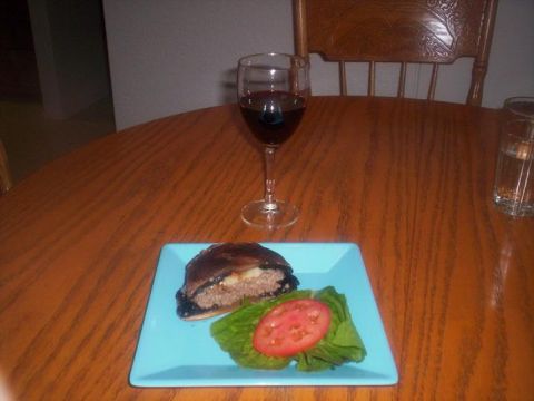 1989 Ford Bronco - A meal of a burger and tomato slice on lettuce, accompanied by a glass of red wine, is presented on a wooden table.