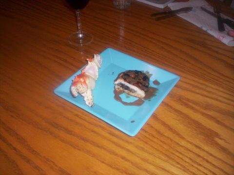 1989 Ford Bronco - A crab claw and stuffed chicken are served on a blue plate next to a glass of red wine on a wooden table.