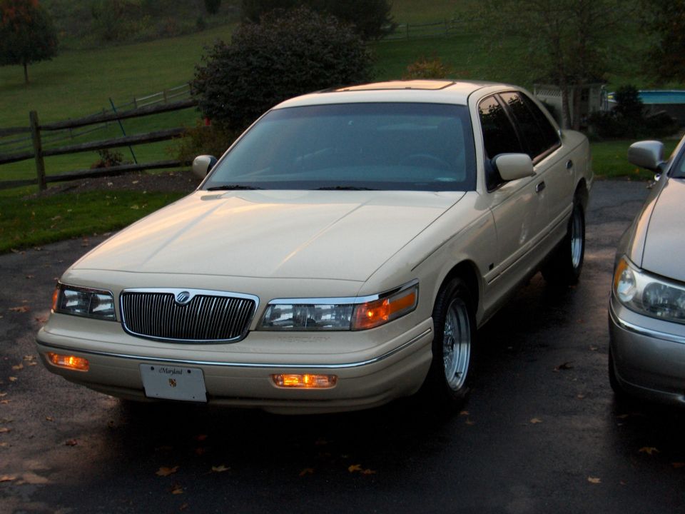 Cream Mercury Grand Marquis sedan, front 3/4 view, parked on driveway