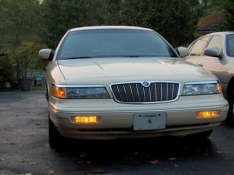 1996 Mercury Grand Marquis - A cream-colored Mercury Grand Marquis is parked outside, with another similar vehicle partially visible behind it.