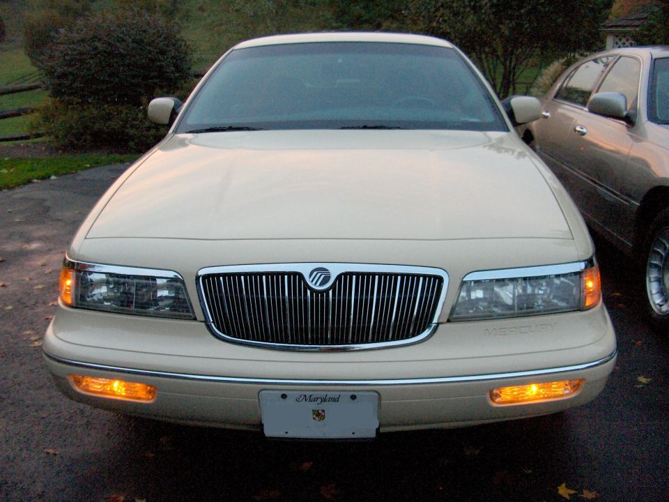 Front view of a cream Mercury Grand Marquis with chrome grille and amber lights lit, Maryland front plate