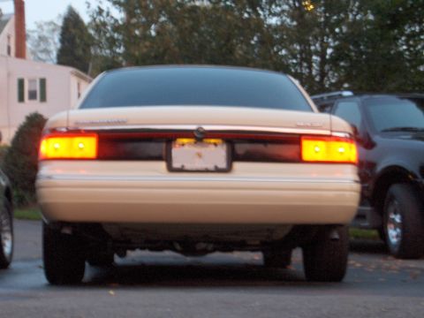 1996 Mercury Grand Marquis - Rear view of a tan sedan parked next to a dark vehicle.