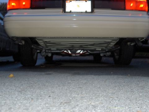 1996 Mercury Grand Marquis - The underside of a beige sedan is visible, revealing the fuel tank and exhaust system.