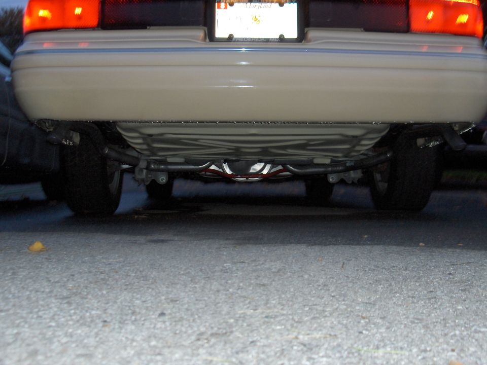 Rear underside view of tan sedan showing suspension and exhaust with Maryland plate above