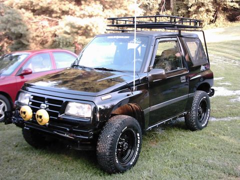 1996 Chevrolet Tracker - This black SUV is equipped with a roof rack and auxiliary lights on the front bumper.