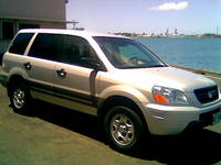 1991 Ford Bronco - This SUV is parked outdoors near the water with a clear sky and some distant structures.