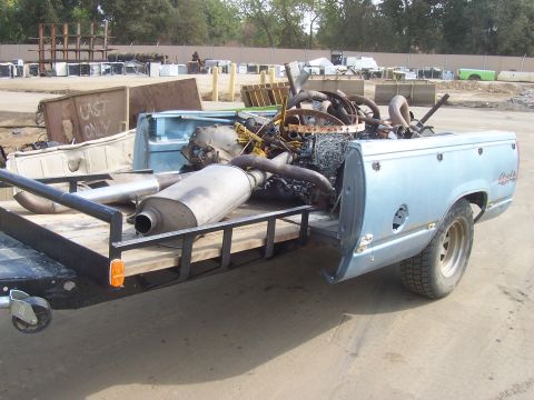 1994 Ford F-150 - A light blue pickup truck bed, possibly a 1994 Ford F-150, is filled with scrap metal and engine components.