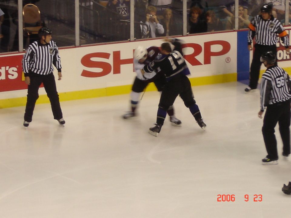 hockey players fighting on ice with referees watching