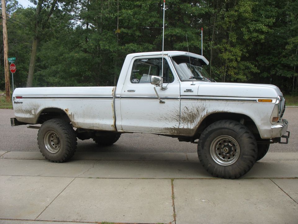 White 1970s Ford pickup with mud, side view on a residential street