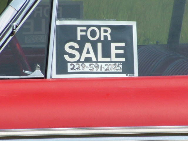 Red car door with a "FOR SALE" sign showing a phone number