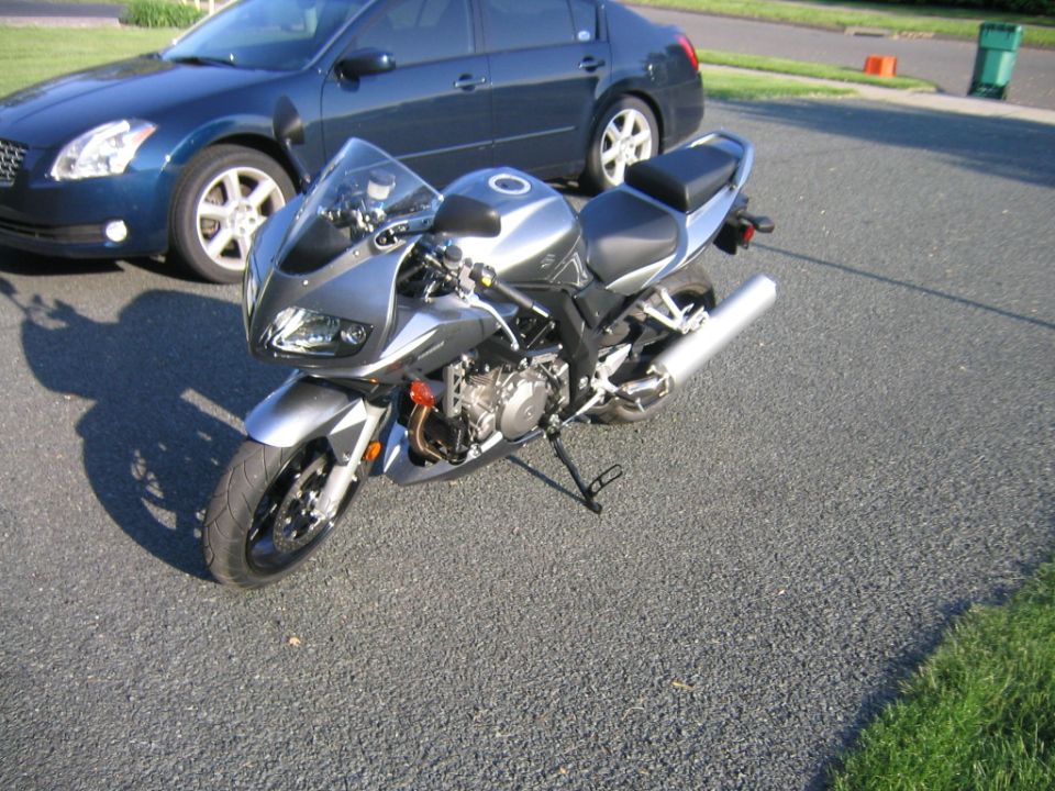 Silver 2006 Suzuki SV1000S motorcycle parked next to a blue sedan