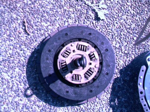 1987 Ford Bronco II - A vehicle clutch disc and pressure plate are shown laid out on a gravel surface.
