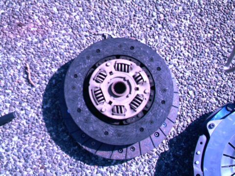 1987 Ford Bronco II - A clutch assembly is shown on a gravel surface, with another part of a clutch visible to the right.