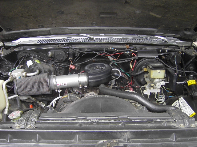 Engine bay with an aftermarket K&N air filter and intake tube. Master cylinder and brake booster visible