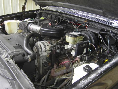 1990 Chevrolet Suburban - The engine bay of a 1990 Chevrolet Suburban is captured in this detailed photograph, highlighting various components.