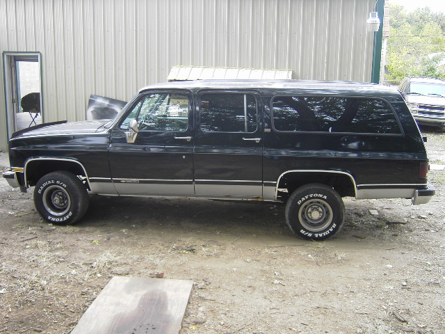 Side view of black 1990 Chevrolet Suburban with chrome trim and Dayton tires