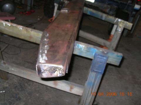 1991 Ford F-150 - A red rear bumper part is shown resting on sawhorses in a workshop.
