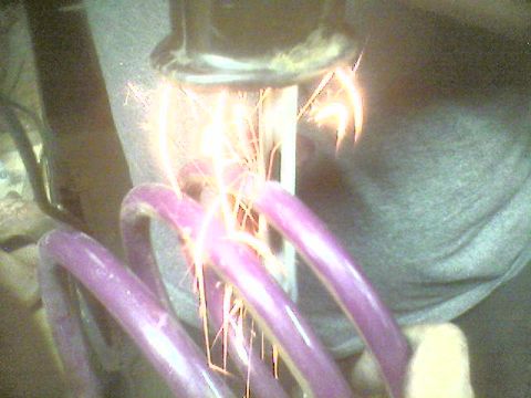 1993 Ford Taurus - Close-up of a purple coil spring with sparks generated from a tool.