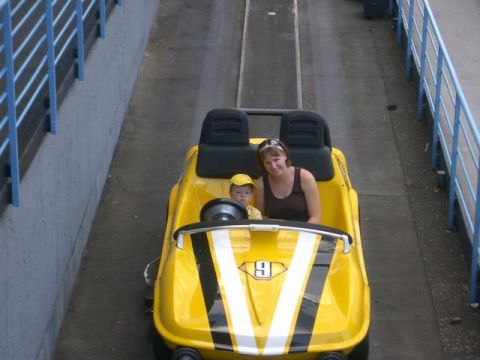 1995 Ford Bronco - Woman and child ride in a yellow amusement park car on a track.