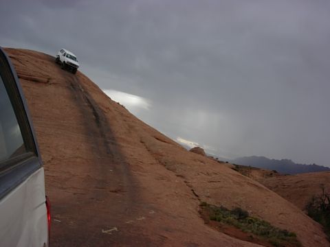1993 Ford Bronco - A white 1993 Ford Bronco navigates a challenging ascent on a rocky desert landscape.