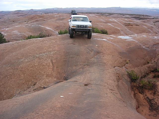 White 1992 Ford F-150 driving on a red rock trail with another SUV behind it