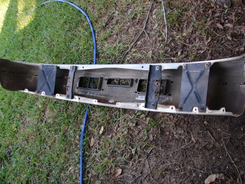 1996 Ford Bronco - A detached vehicle bumper lies on the ground, showing its internal mounting points and ventilation slots.