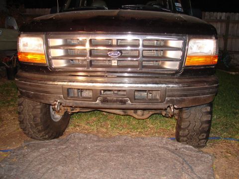 1996 Ford Bronco - The front grille and bumper of a black Ford Bronco are shown, with tow hooks attached.