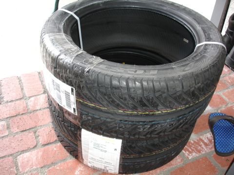 1993 Ford Taurus - Several new tires are stacked and secured with plastic wrap and shipping labels.