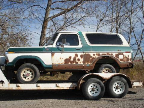 1979 Ford Bronco - This weathered Ford Bronco is being transported on a trailer under a clear sky.