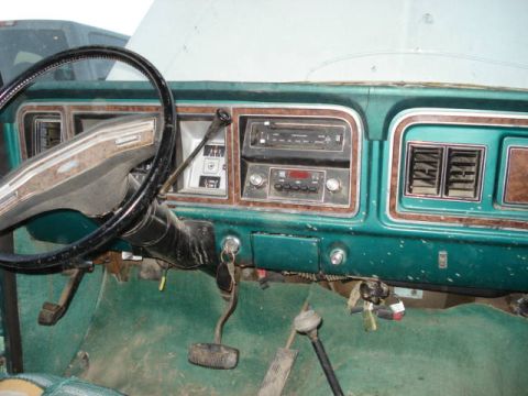 1979 Ford Bronco - Interior view of a 1970s Ford truck or SUV dashboard, woodgrain accents and a floor-mounted shifter.