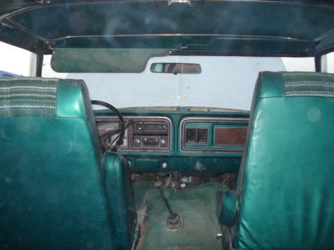 1979 Ford Bronco - The interior of a vintage Ford Bronco shows green vinyl seats and a dashboard with a radio and vents.
