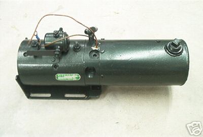 1990 Ford Bronco - Dark green hydraulic pump and electric motor assembly on a black mounting bracket, photographed against a plain white background. Small sol…