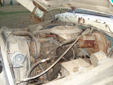 1979 Ford Bronco - The engine bay of an older vehicle is shown with various components and some rust.