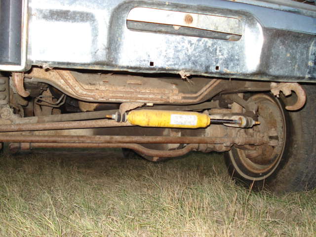 Undercarriage view of a vehicle's suspension with a yellow shock absorber