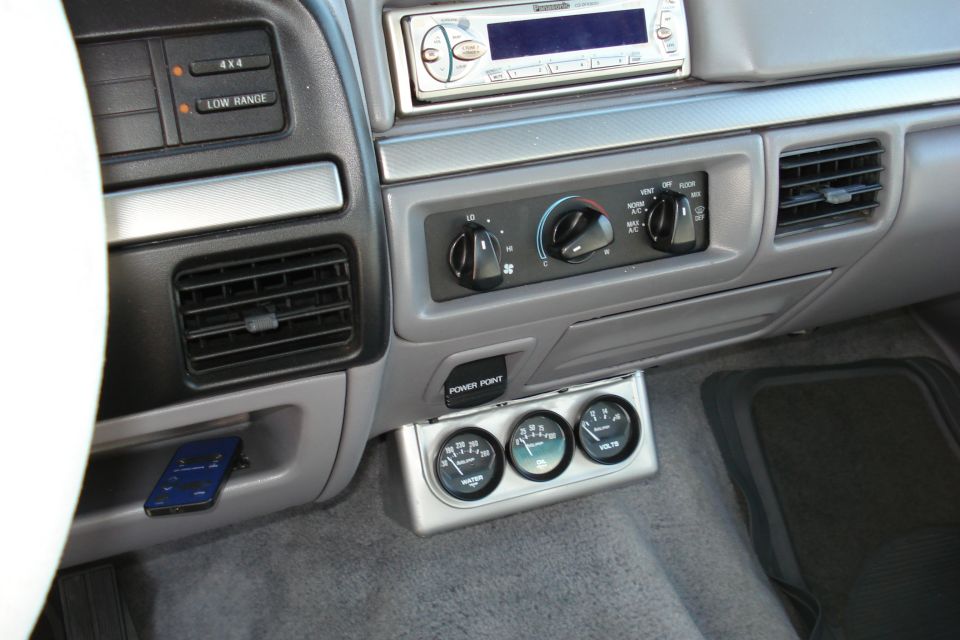 1994 Ford Bronco interior showing dashboard, radio, climate controls, and aftermarket gauges