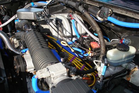 1994 Ford Bronco - A close-up view of a vehicle's engine bay, numerous wires and hoses.