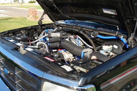 1994 Ford Bronco - Engine bay of a black Ford Bronco, showing the engine and various components under the open hood.