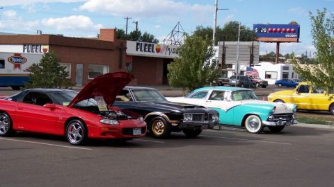 1972 Ford Ranchero - A variety of vehicles are parked in a lot, including a modern sports car and several older models.