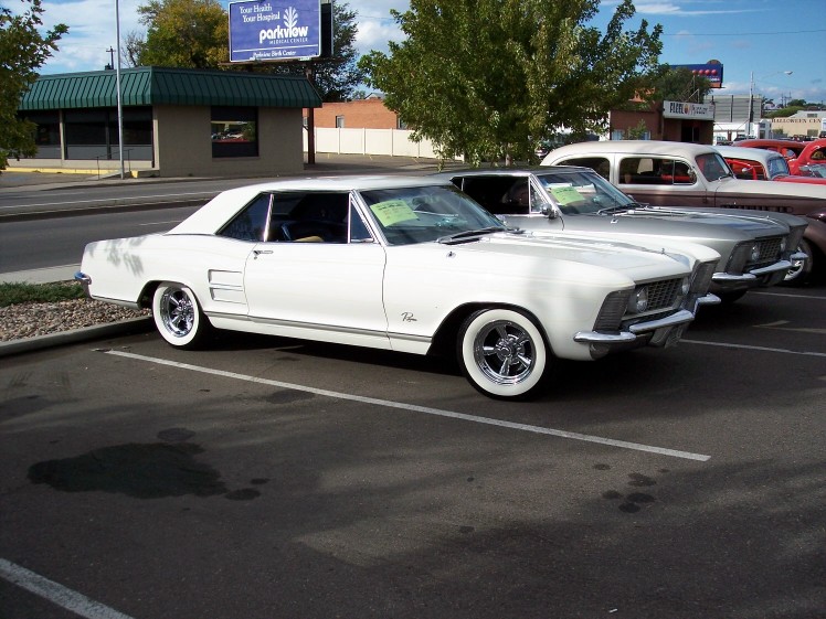 white coupe parked next to other cars