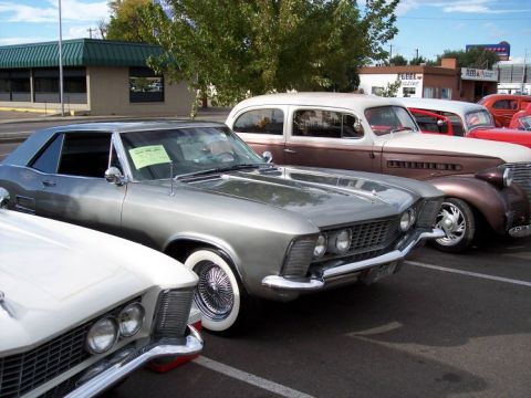 1972 Ford Ranchero - A collection of classic automobiles are lined up in a parking lot under a partly cloudy sky.