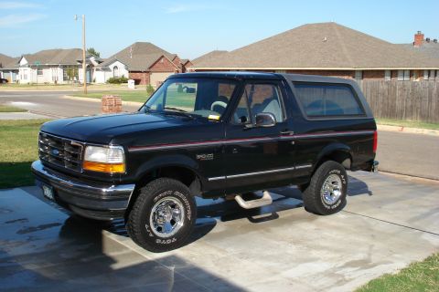 1994 Ford Bronco - Black Ford Bronco parked on a driveway with houses in the background.