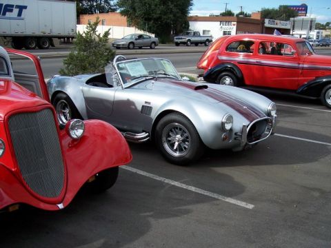 1972 Ford Ranchero - A silver Shelby Cobra replica and a red hot rod are parked side-by-side at an outdoor car show.