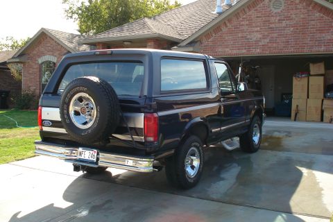 1994 Ford Bronco - Rear view of a black Ford Bronco parked in front of a brick house and garage.
