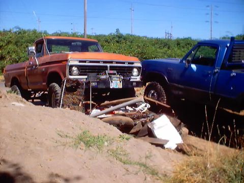 1976 Ford F-100 - Orange pickup truck with a winch on the front bumper, parked next to a blue truck.