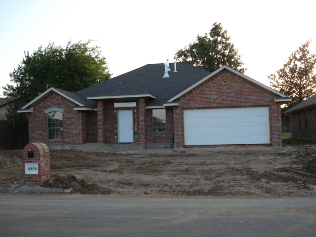 Brick house with white garage door and mailbox showing '4909'